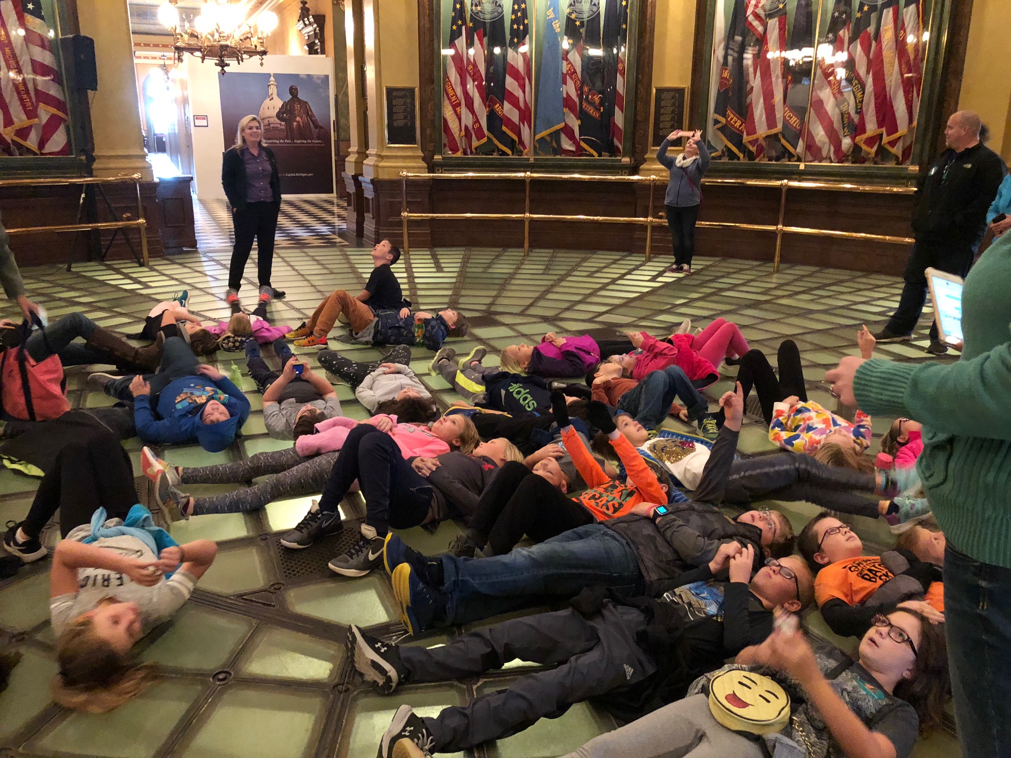 students laying on ground looking at architecture on field trip